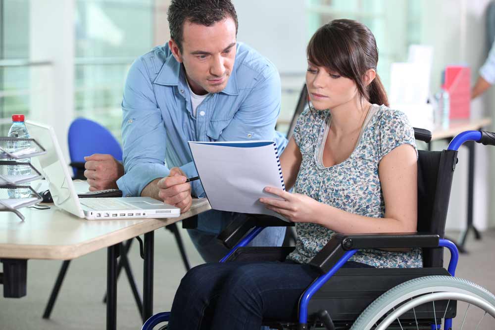 Young woman in wheelchair working with a male colleague.