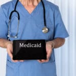 medicaid written on a tablet being held by a nurse