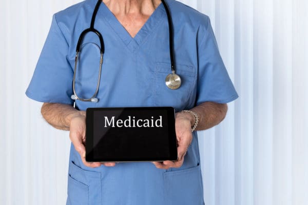 medicaid written on a tablet being held by a nurse