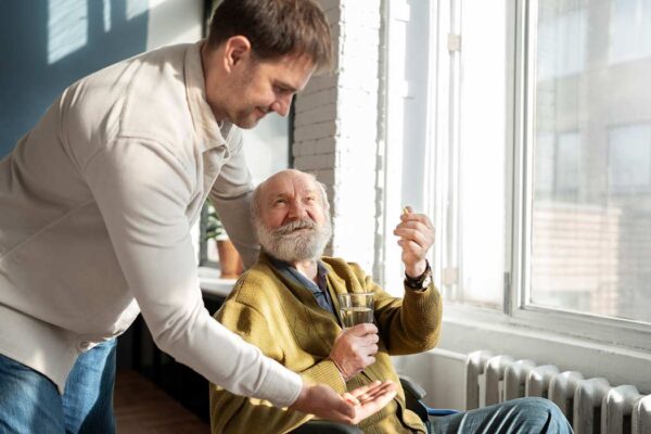 caregiver son giving medications to elderly disabled father