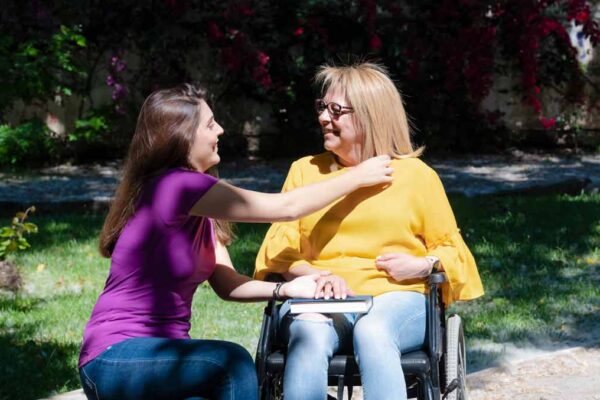 daughter outdoors with disabled mother in a wheelchair