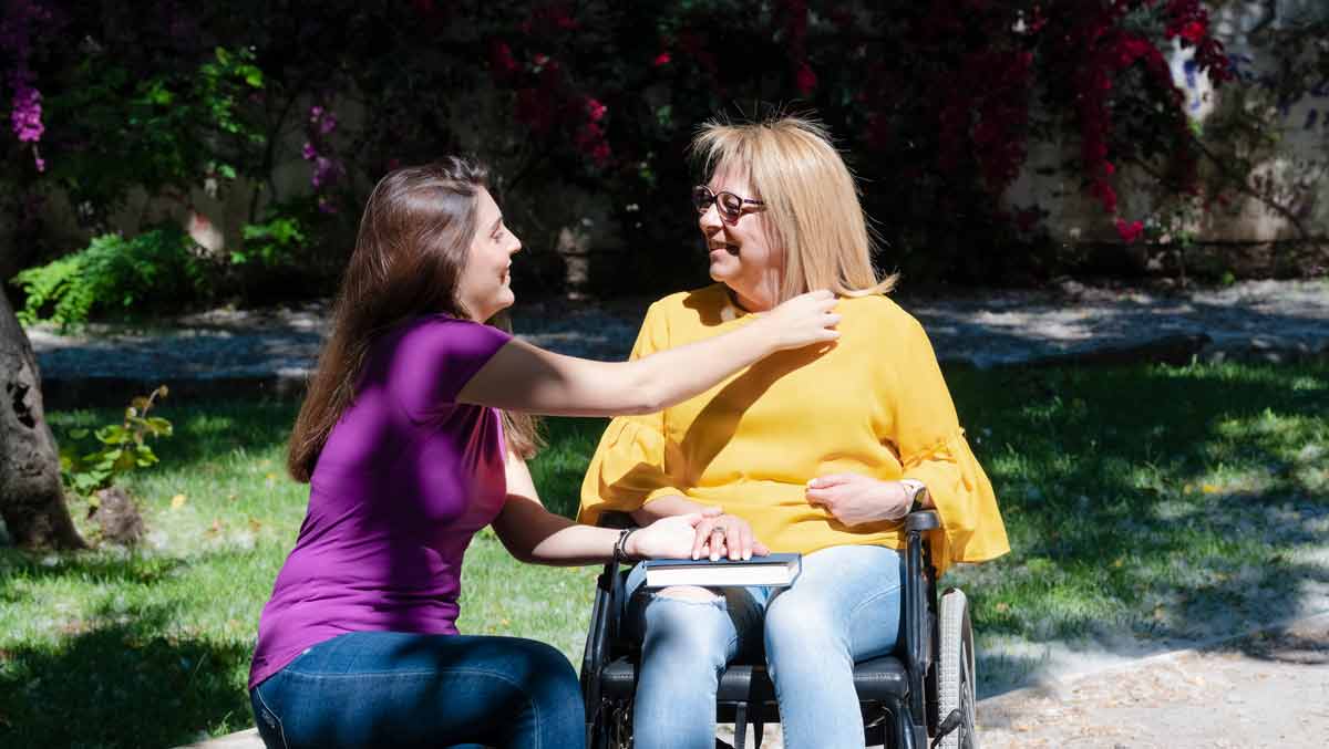 daughter outdoors with disabled mother in a wheelchair