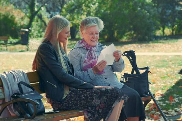 daughter caregiver with senior mother in a park sitting