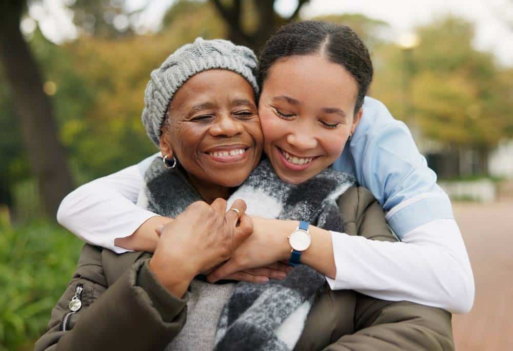 caregiver daughter hugging senior disabled mother