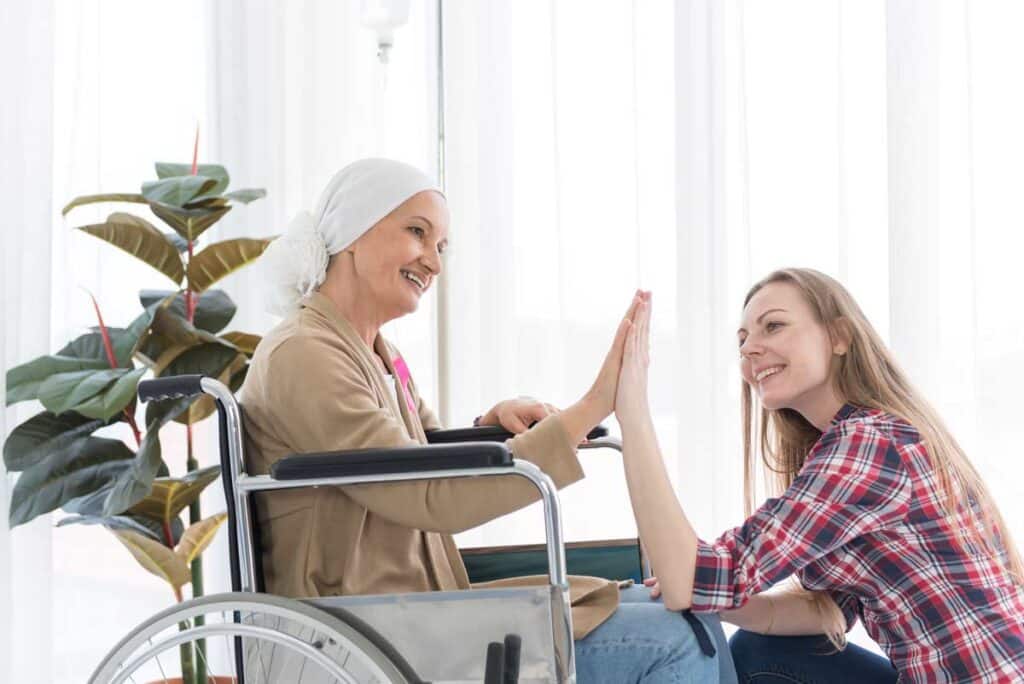 daughter caregiver holding hand of disabled mother in wheelchair