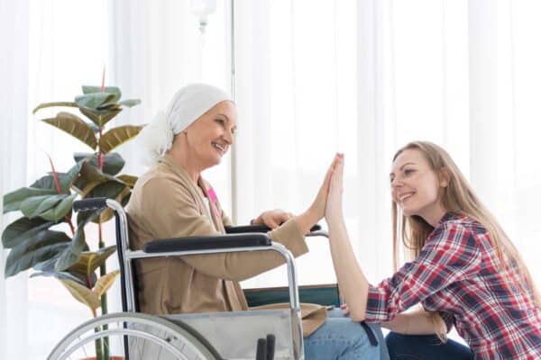 daughter caregiver holding hand of disabled mother in wheelchair