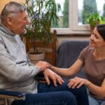 smiling daughter caregiver holding disabled father's hand