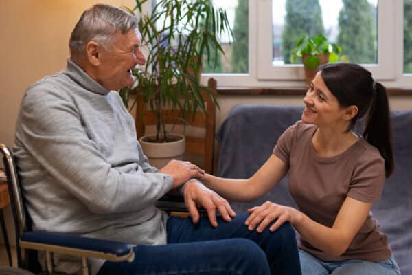 smiling daughter caregiver holding disabled father's hand