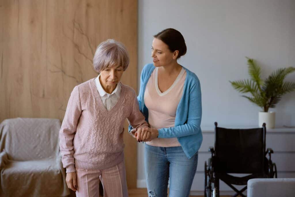 caregiver helping elderly woman walking