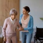 caregiver helping elderly woman walking