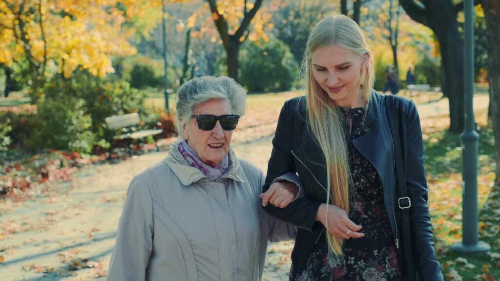 daughter helping elderly mother walking in the park