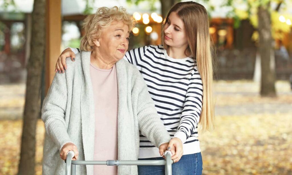 granddaughter helping grandma walking in the park with a walker