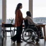 caregiver helping patient in wheelchair at home