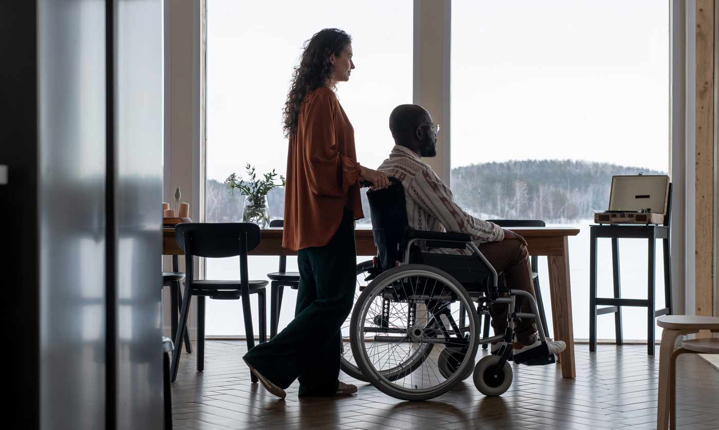 caregiver helping patient in wheelchair at home