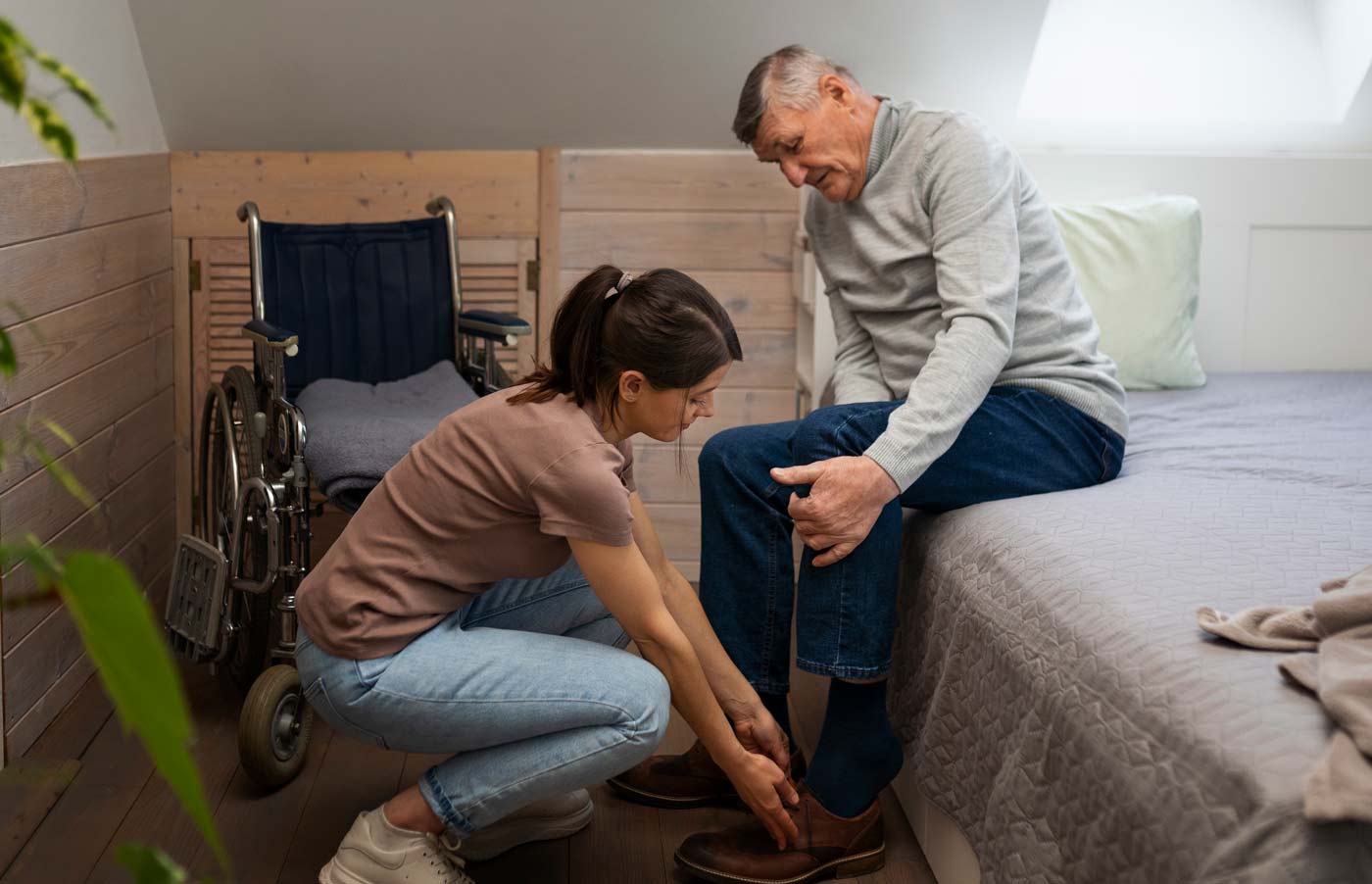 young caregiver woman helping elderly man put of shoes