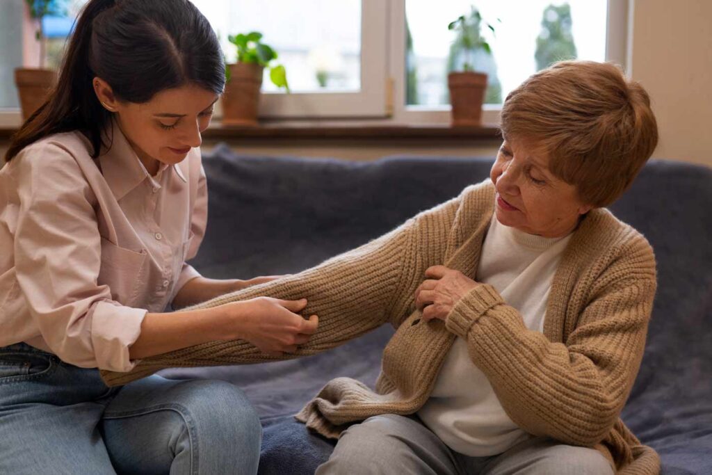 family caregiver helping elderly woman to dress up