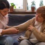 family caregiver helping elderly woman to dress up