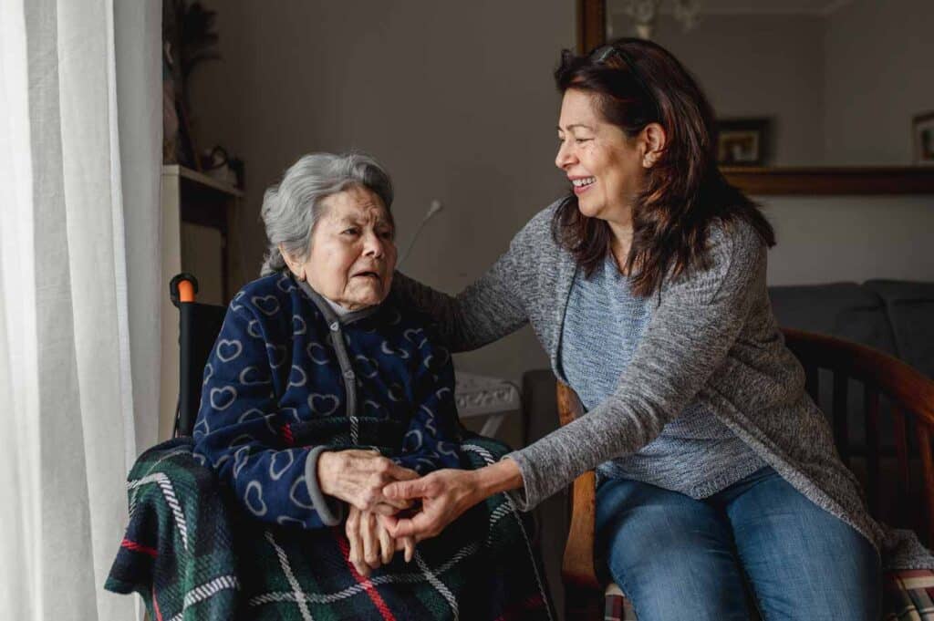 elderly woman in wheelchair being helped from family member in home care