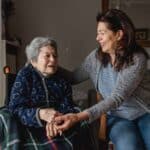 elderly woman in wheelchair being helped from family member in home care