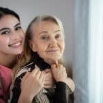 smiling female caregiver holding elderly woman