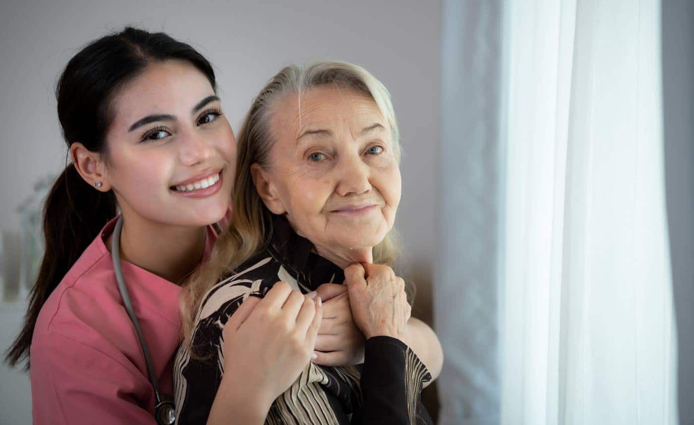 smiling female caregiver holding elderly woman