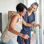 caregiver helping patient get out of bed walking