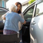 caregiver helping elderly woman go into the car