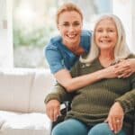 caregiver holding patient in wheelchair smiling