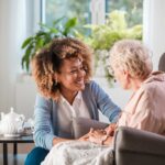 caregiver smiling with elderly disabled patient