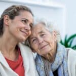 caregiver daughter holding closely elderly mother