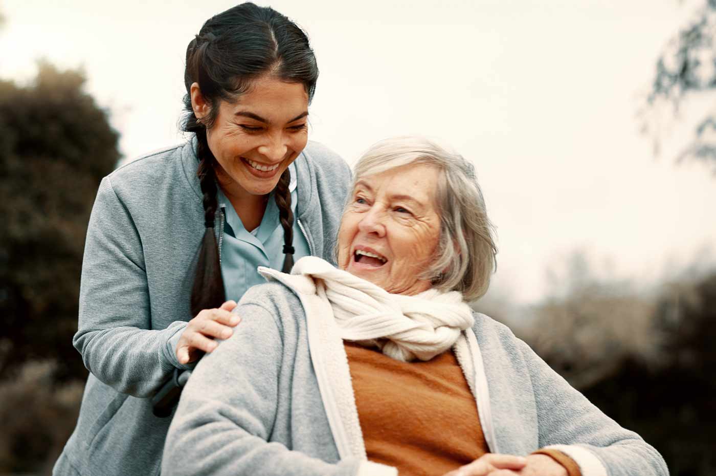 caregiver taking elderly woman in wheelchair outdoor for a walk