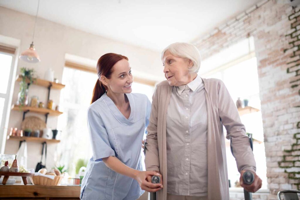 caregiver helping elderly woman patient walking