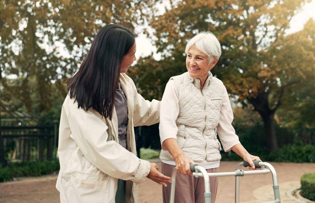 family caregiver helping mother walk outdoors