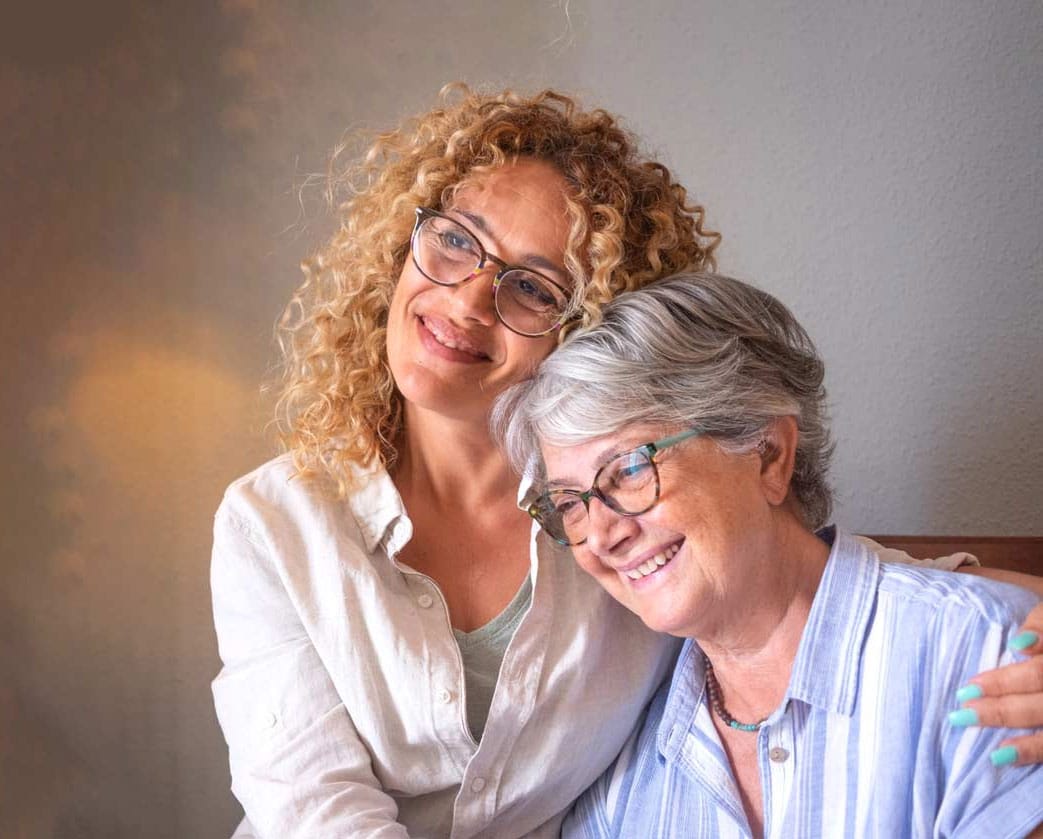 A caregiver hugging an elderly loved one at home